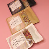 All three of the Poppy California Bath Salt Packets on a pink background.