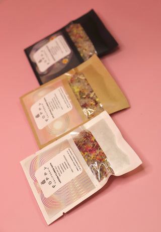 All three of the Poppy California Bath Salt Packets on a pink background.