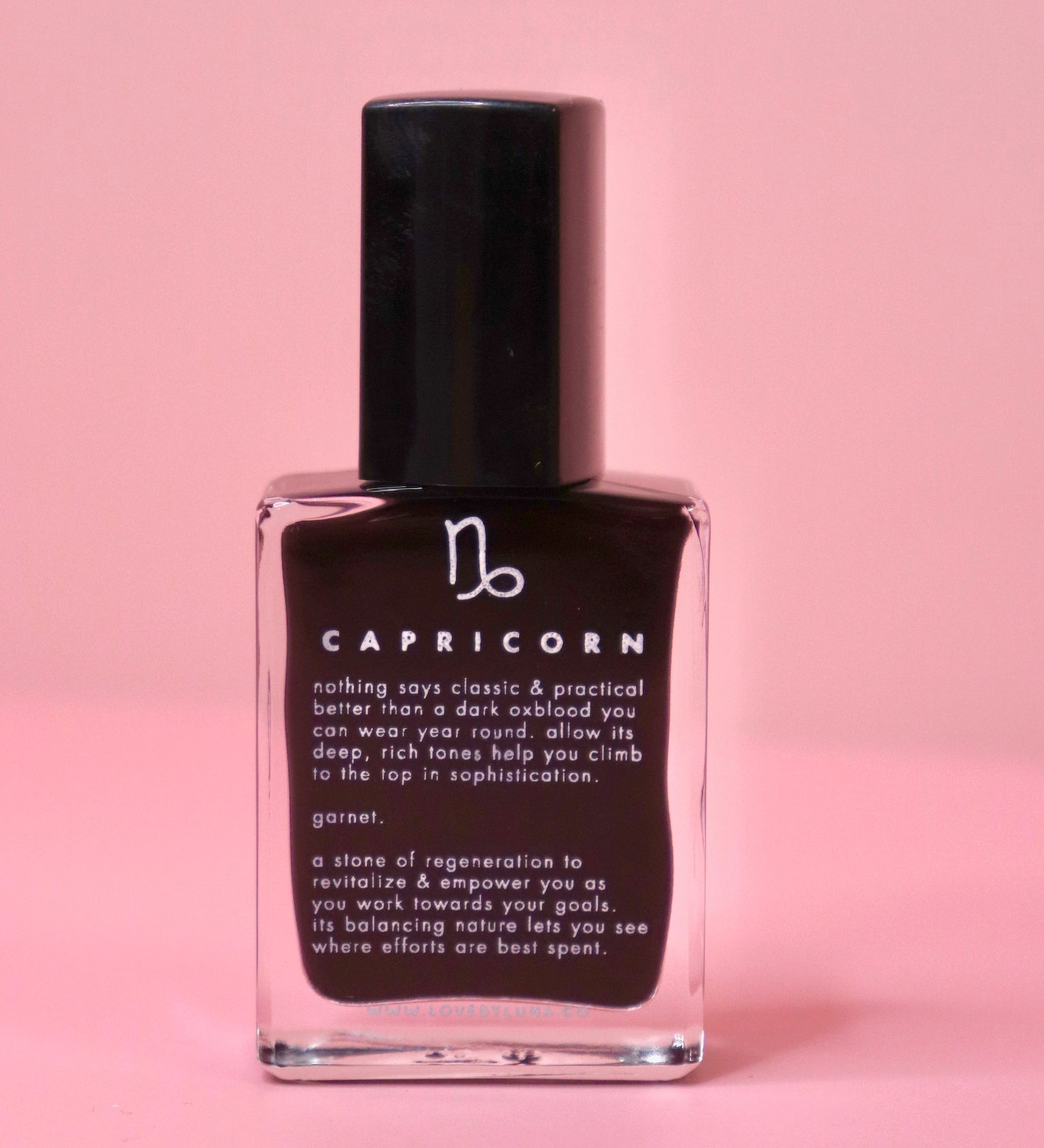 The Capricorn Zodiac Nail Polish with Micronized Garnet on a pink background.