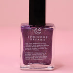 The Luminous Dreams Nail Polish with Micronized Amethyst on a pink background.