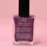 The Luminous Dreams Nail Polish with Micronized Amethyst on a pink background.
