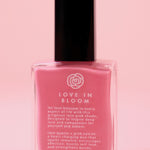 The Love in Bloom Nail Polish with Micronized Rose Quartz & Pink Calcite on a pink background.