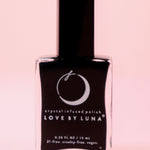 The New Moon Nail Polish with Micronized Selenite, Moonstone, & Clear Quartz on a pink background.