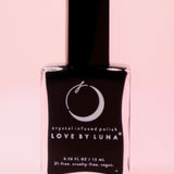 The New Moon Nail Polish with Micronized Selenite, Moonstone, & Clear Quartz on a pink background.