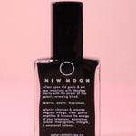 The New Moon Nail Polish with Micronized Selenite, Moonstone, & Clear Quartz on a pink background.
