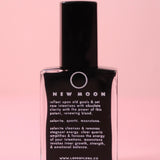 The New Moon Nail Polish with Micronized Selenite, Moonstone, & Clear Quartz on a pink background.
