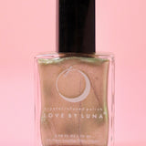 The Abundance Boost Nail Polish with Micronized Pyrite on a pink background.