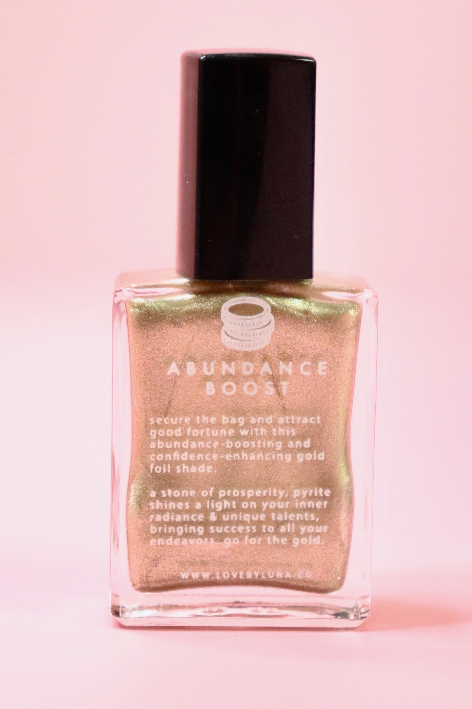 The Abundance Boost Nail Polish with Micronized Pyrite on a pink background.