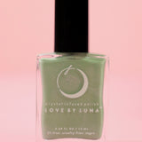 The Manifestation Magic Nail Polish with Micronized Green Aventurine on a pink background.
