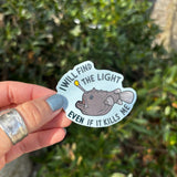 The Anglerfish Vinyl Sticker being held in front of greenery.