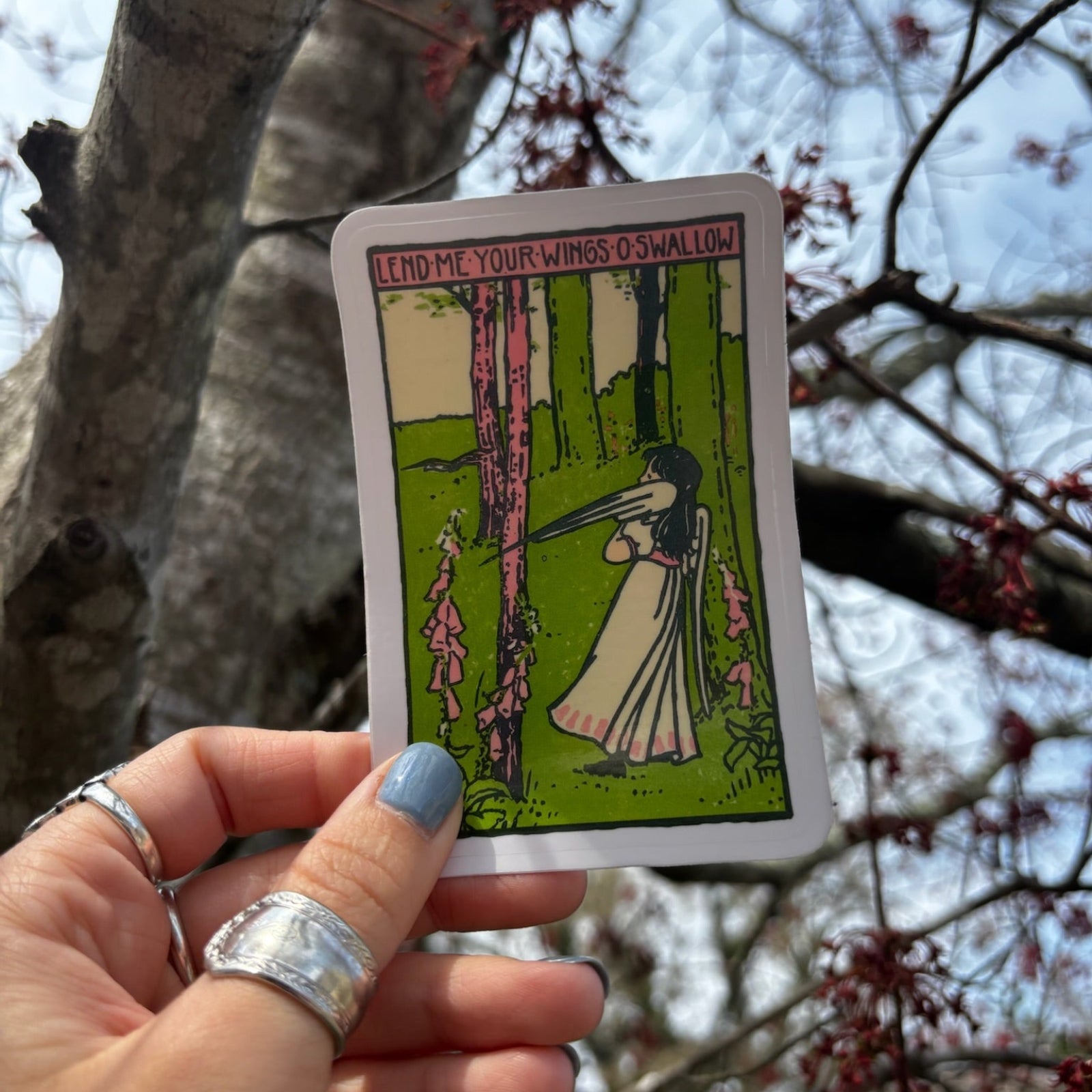 Someone holding the Lend Me Your Wings O Swallow 3 Inch Sticker in front of a tree.