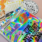 The Fun Mystery Sticker Bag on a pink background with stickers surrounding it.