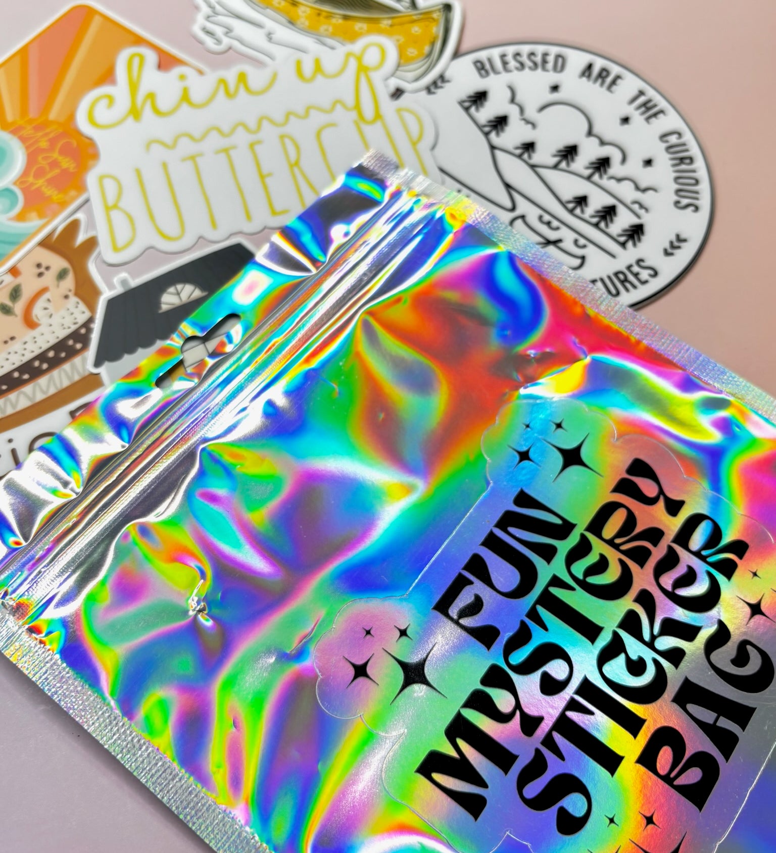The Fun Mystery Sticker Bag on a pink background with stickers surrounding it.