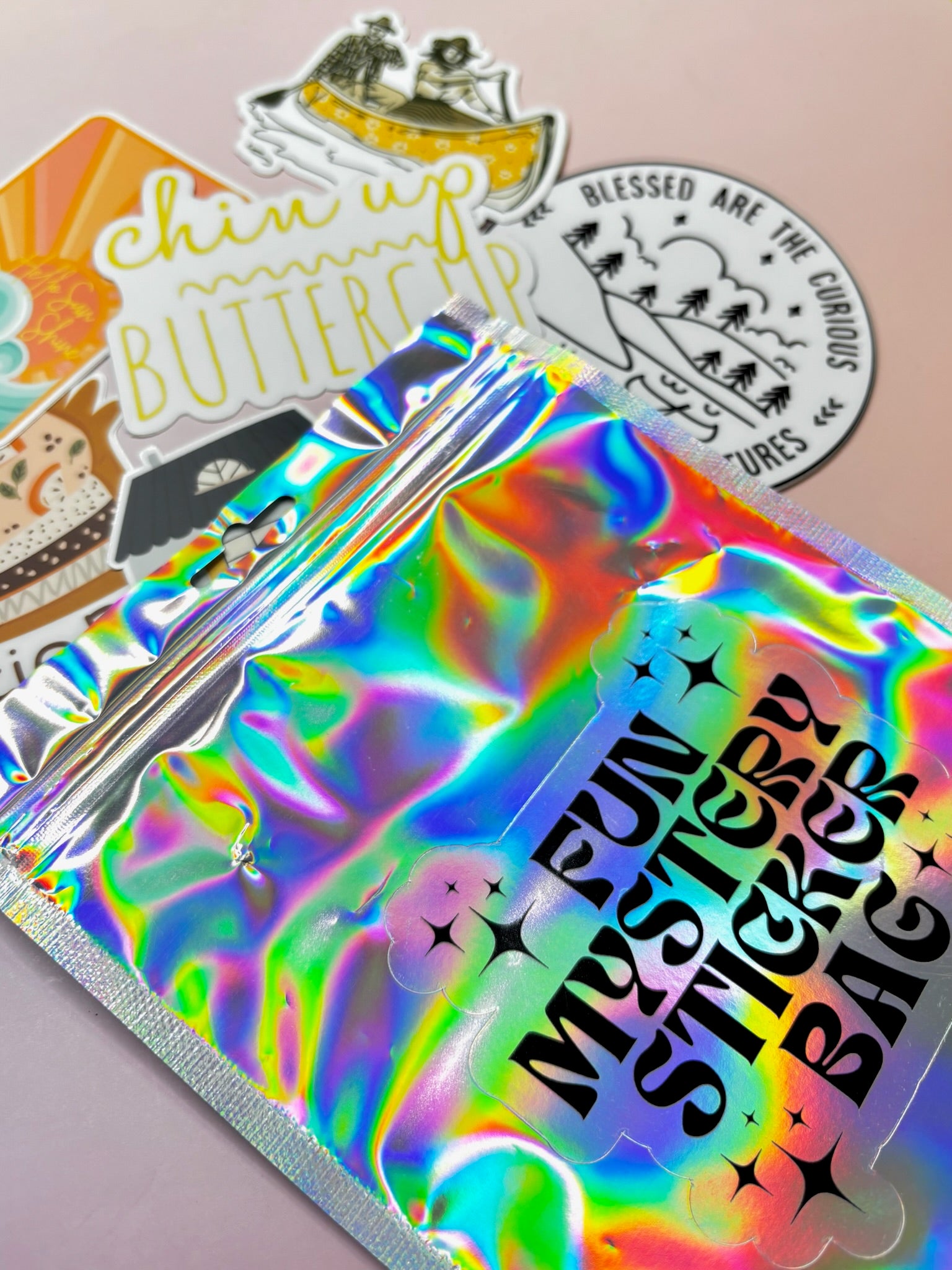 The Fun Mystery Sticker Bag on a pink background with stickers surrounding it.