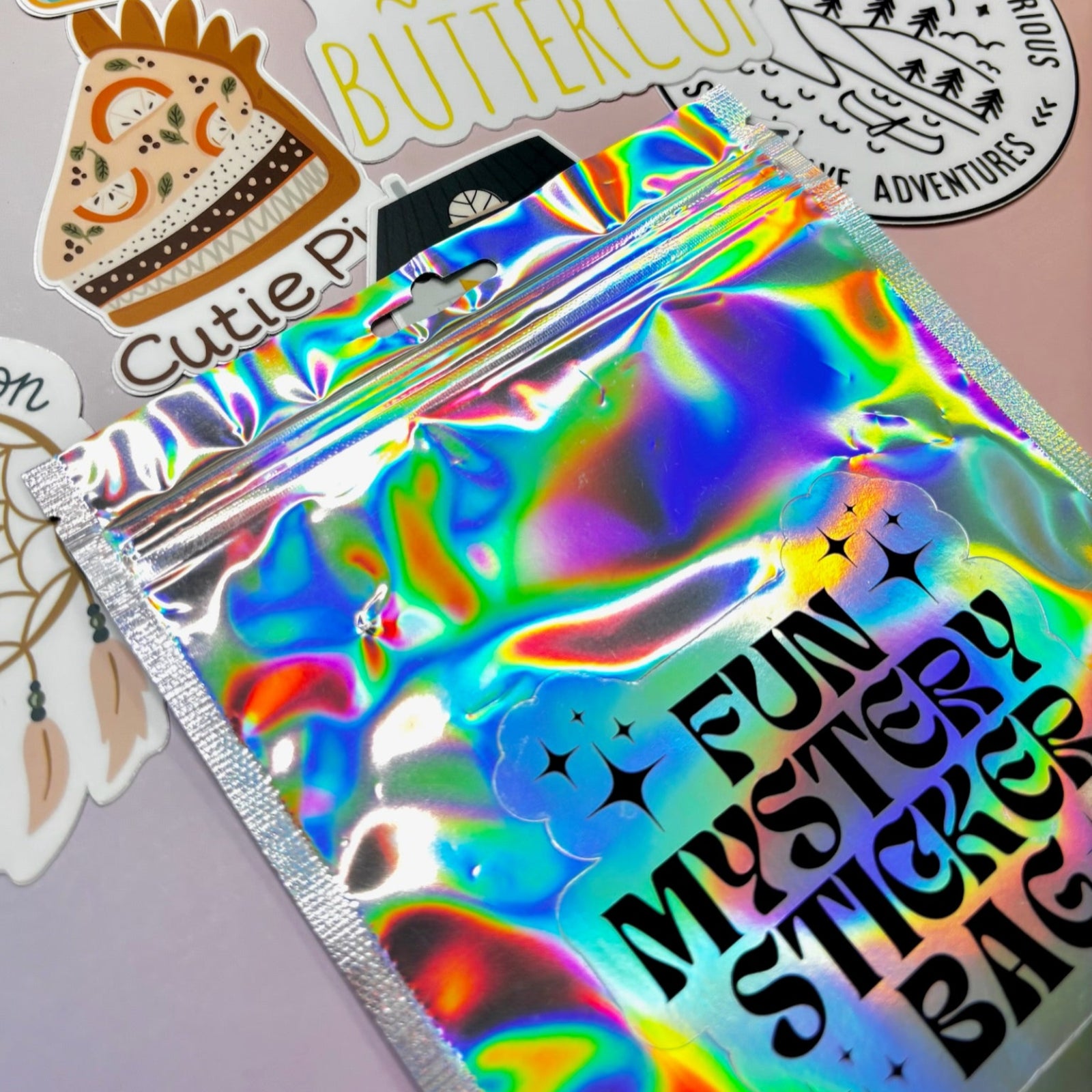 The Fun Mystery Sticker Bag on a pink background with stickers surrounding it.