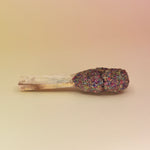 The '7 Chakras' Palo Santo Pop - 3"-4" Smudge Stick on a pink and yellow background.