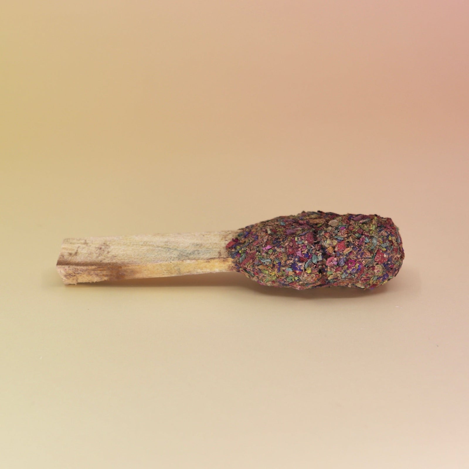 The '7 Chakras' Palo Santo Pop - 3"-4" Smudge Stick on a pink and yellow background.