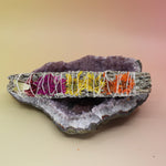 The 'Joy' Floral White Sage Smudge Stick. on an amethyst piece all on a pink and yellow background.