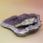 The California White Sage Torch 4 in. on an amethyst piece on a pink and yellow background.