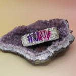 The 'Blissful' Floral White Sage Smudge Stick 4 in. on an amethyst piece all on a pink and yellow background.