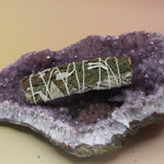 The Organic White Sage & Cedar - 4 in. Purifying and Balancing Smudge Stick on an amethyst piece all on a pink and yellow background.