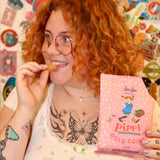 A woman holding the Pippi Longstocking Gold Coins bag with one candy in her left hand.