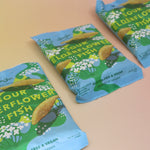 Three bags of the BonBon NYC Sour Elderflower Fish - Swedish Candy on a pink and yellow background.