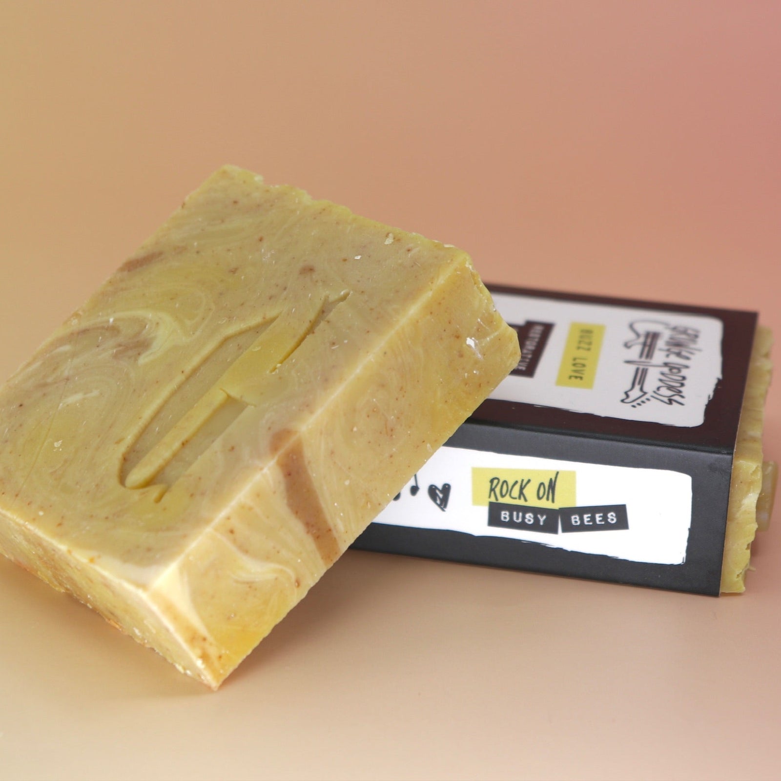 Two of the Buzz Love - Restorative Honey Oat Soaps on a peach-colored background.