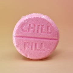 The Chill Pill Bubble Bath Bomb on a peach colored background.
