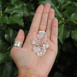 Someone holding multiple Herkimer Diamond Stones in front of a green nature background.