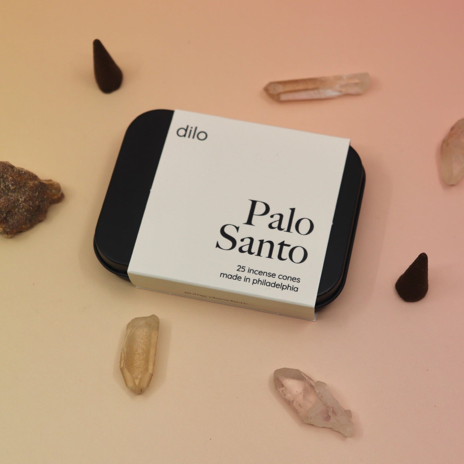The Palo Santo Incense Cones container surrounded by crystals and incense cones.