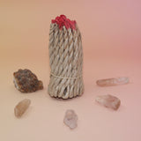 The Nepalese Himalayan Hand Rolled Incense Ropes with crystal points surrounding it all on a light pink and yellow background.