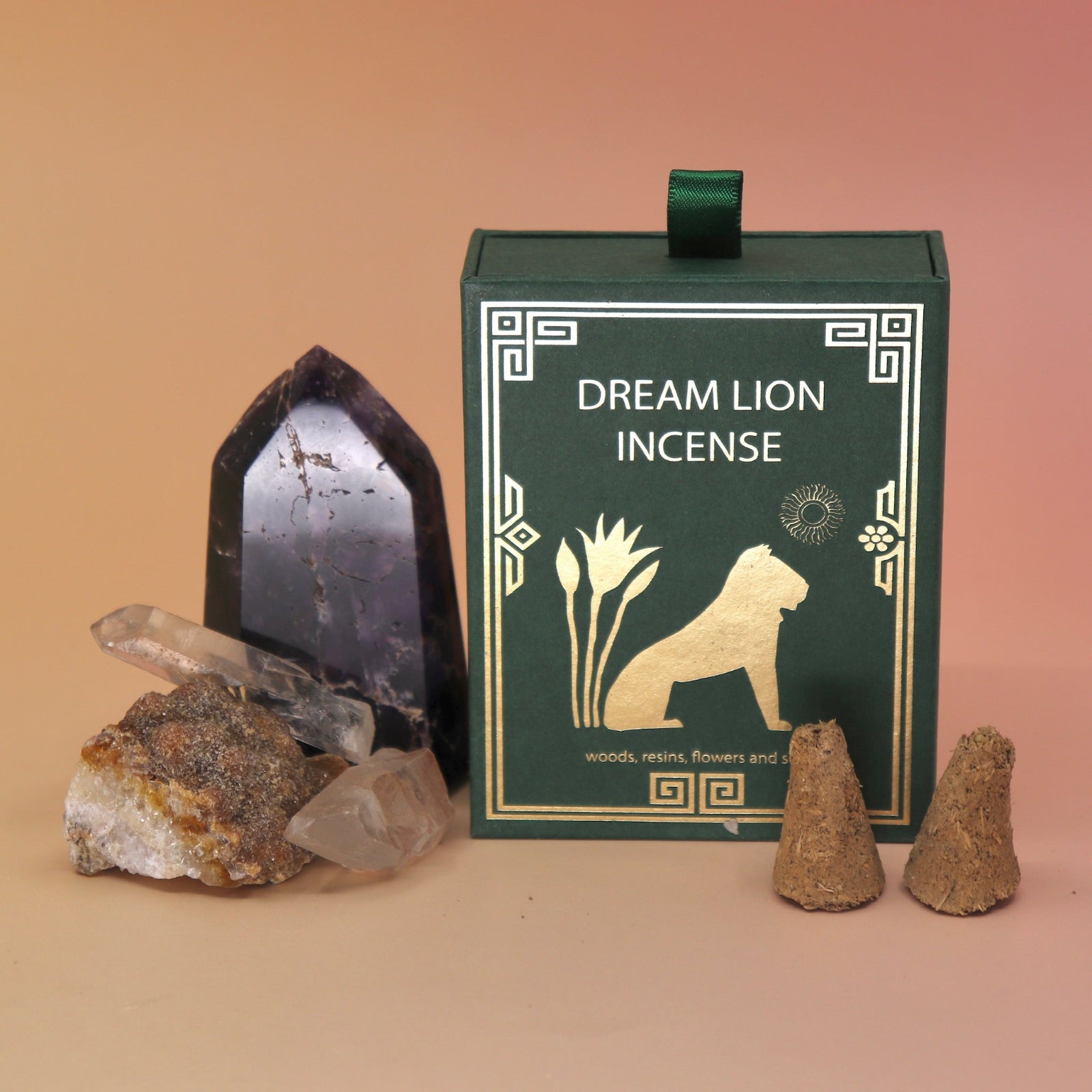 The Mayan Copal + Desert Sage Incense Cone box next to two crystal pieces with two of its incense cones in front of the box all on a pink and yellow backgrounds.