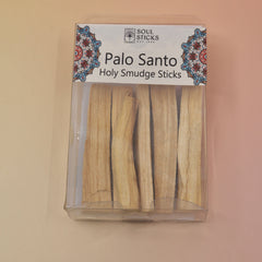 The Holy Smudge Sticks - Pack of 6 4" Palo Santo Sticks on a pink and yellow background.