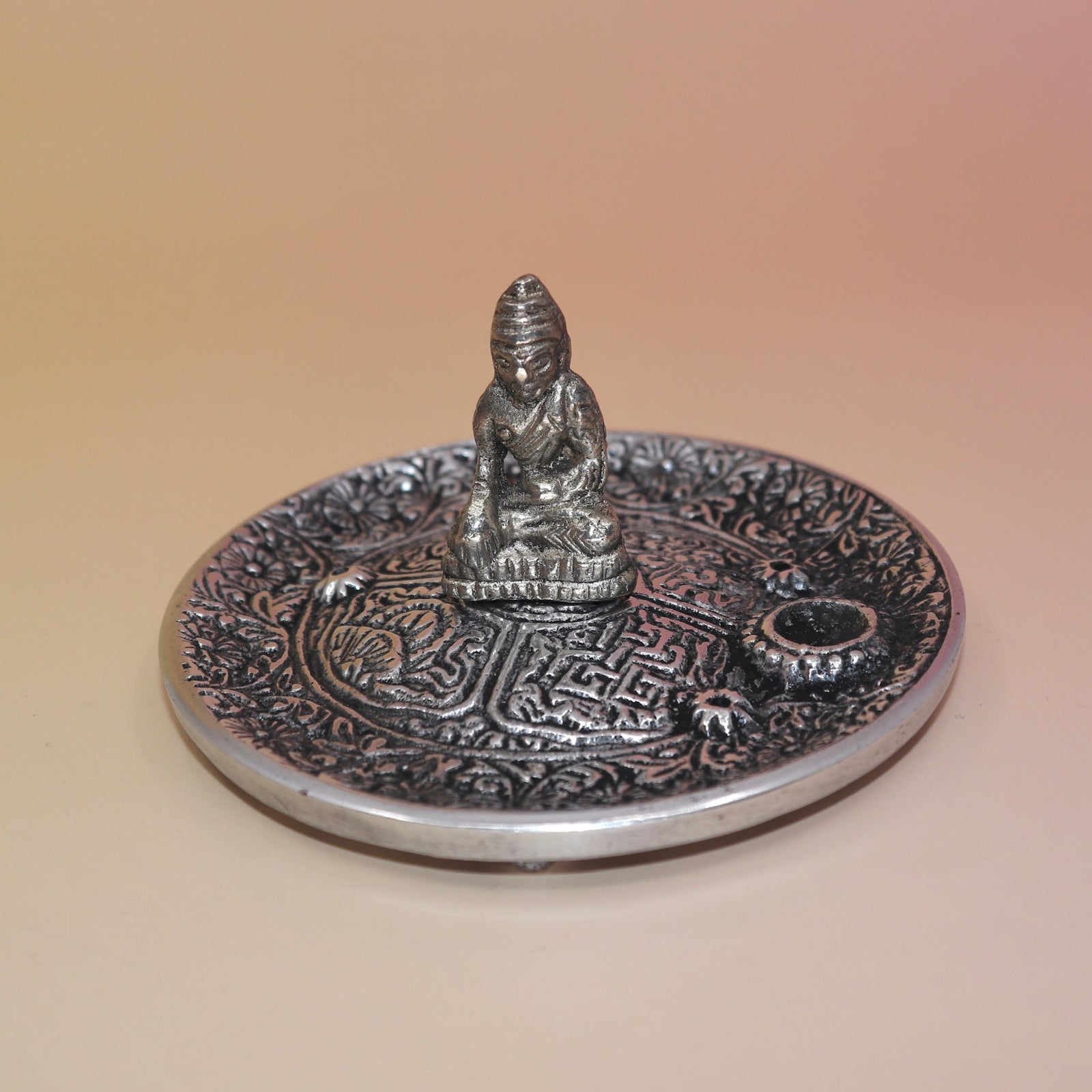 The Silver Buddha Cone and Stick Incense Holder on a pink and yellow background.