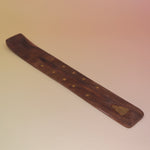 The Buddha Wooden Incense Burner on a pink and yellow background.