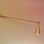 The Brass Candle Snuffer on a pink and yellow background.