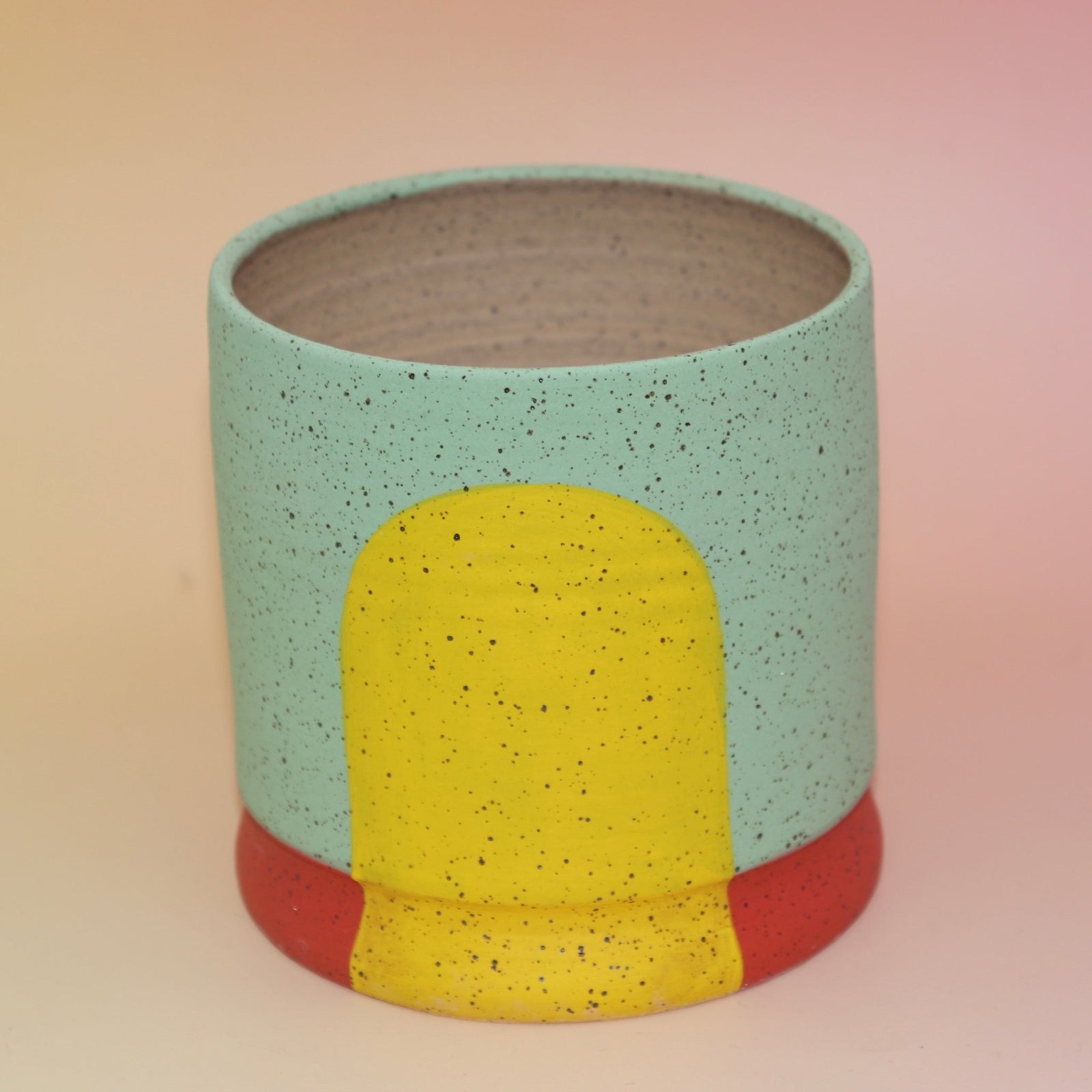 The Betty Multicolored Portal Stoneware 5 in. Planter on a pink and yellow background.