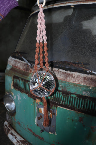 Someone holding the blush and rust Color Dip Disco Ball Hanger - Macrame Plant Hanger in front of a vintage teal Volkswagen bus.