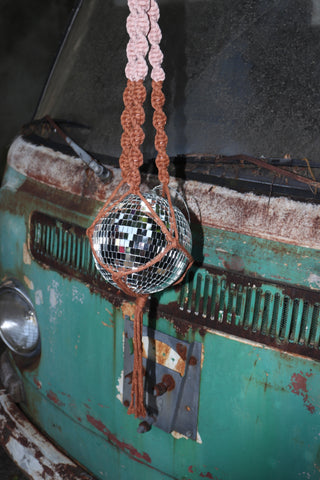 Someone holding the blush and rust Color Dip Disco Ball Hanger - Macrame Plant Hanger in front of a vintage teal Volkswagen bus.
