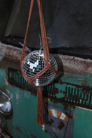 Someone holding the Rust Disco Ball Hanger with Disco Ball in front of a rusted teal Volkswagen bus.