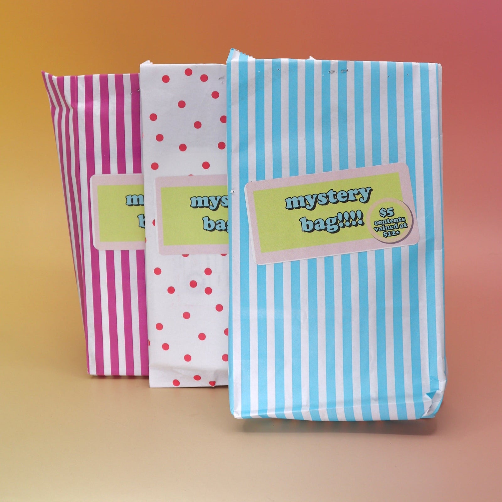 Three 5 Dollar Blind Mystery Bags on a pink and orange background.