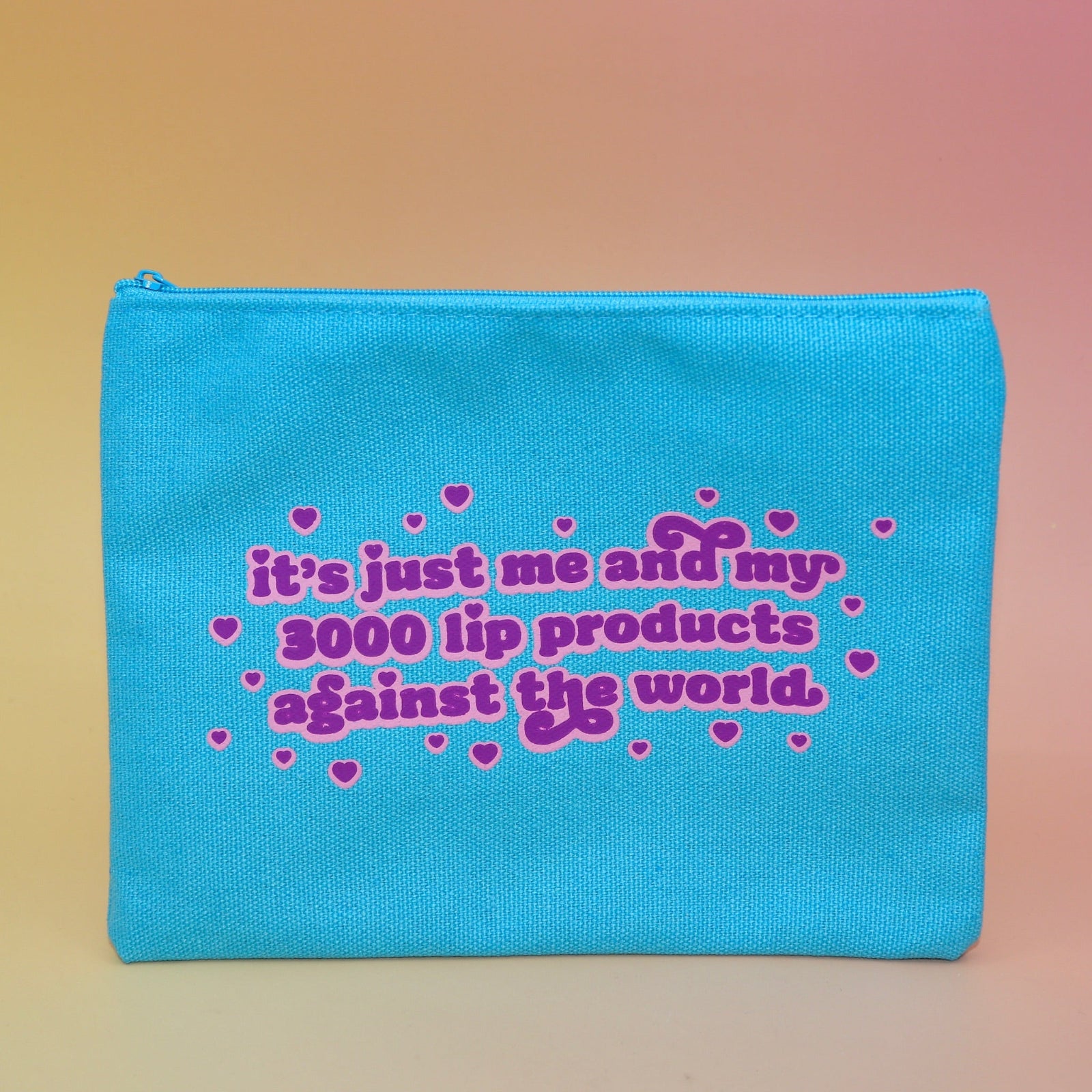 The Me & My Lip Products Against The World Canvas Zipper Pouch on a pink and yellow background.