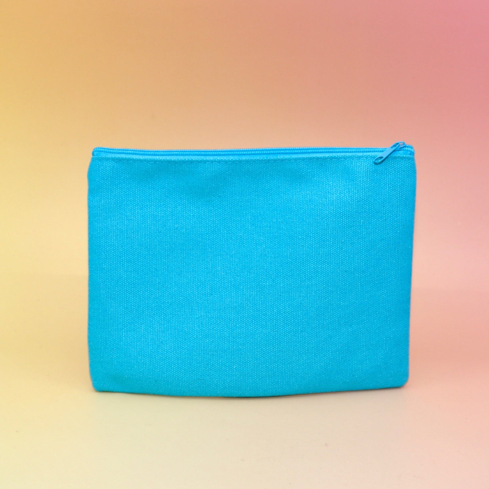 The back of the Me & My Lip Products Against The World Canvas Zipper Pouch on a pink and yellow background.