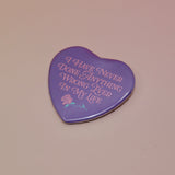 The I Have Never Done Anything Wrong Heart Shaped Pinback Button on a light pink background.
