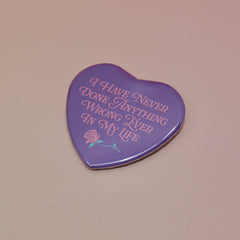 The I Have Never Done Anything Wrong Heart Shaped Pinback Button on a light pink background.