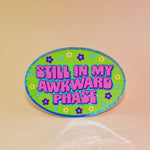 The Still In My Awkward Phase Oval Holographic Glitter Sticker on a light pink background.