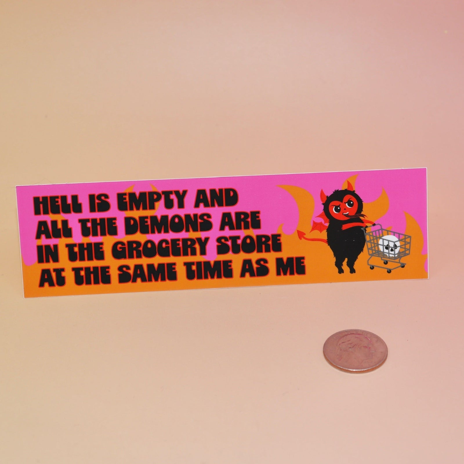 The Hell Is Empty Demons Are In The Grocery Store Vinyl Bumper Sticker next to a quarter on a light pink background.
