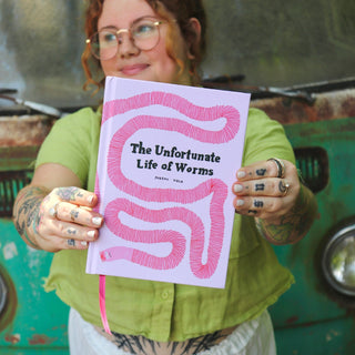 A woman holding The Unfortunate Life of Worms Hardcover Book.