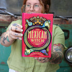 A woman holding the Mexican Witch Lifestyle Hardcover Book.